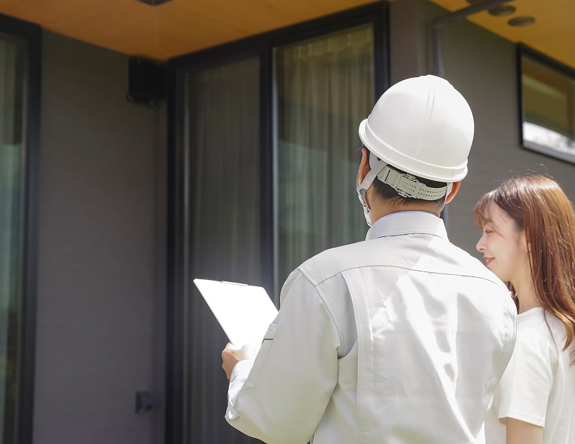 Man in hard hat and woman outside modern building.